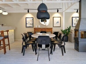 Un comedor moderno con una mesa redonda y sillas, una barra de madera y una estación de parrilla empotrada.
