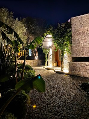 A paved courtyard with a stone wall, a wooden door, and a hanging light fixture. - Dorman Suites Hotel (Bodrum)