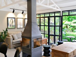 A modern living room with a wood-burning stove, large windows, a sofa, and a dining table. - Dorman Suites Hotel (Bodrum)