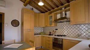 Uma cozinha com armários de madeira, painel de azulejos e um espaço de refeições com mesa e cadeiras.