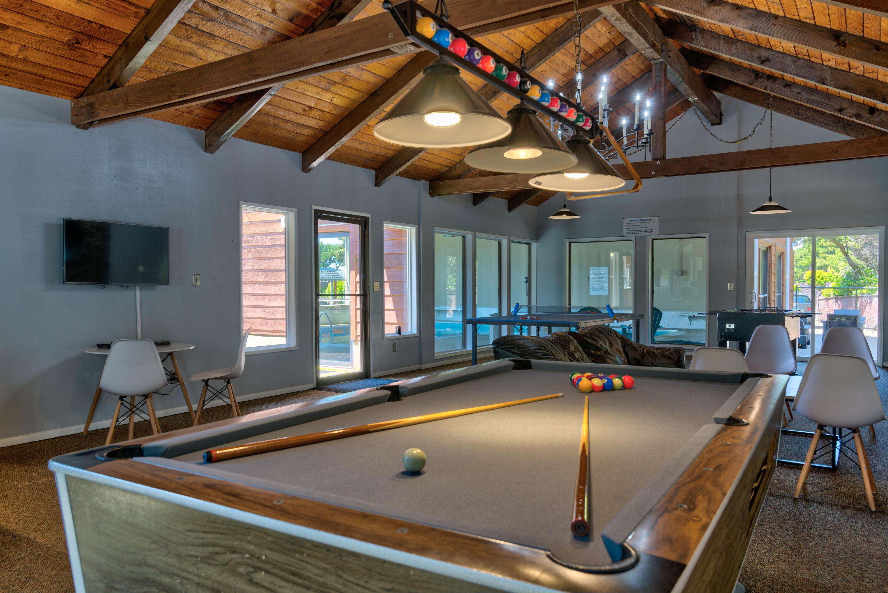 A pool table with balls, a television, and a seating area with chairs.