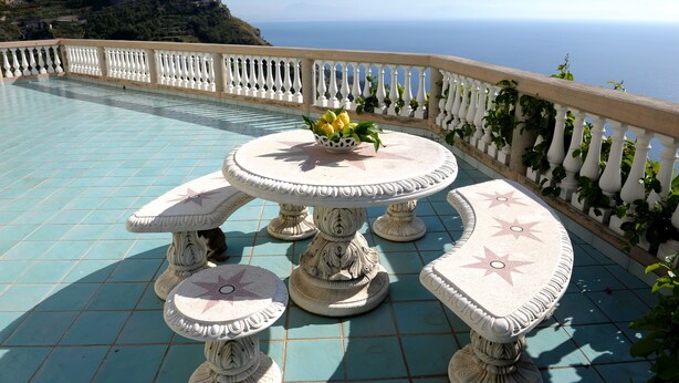 A round table with a flower centerpiece and matching chairs, set on a tiled patio with a railing and a view of the sea. - Stunning views, Space, Charm, Great Pool, Ideal Amalfi Coast location! (Furore)