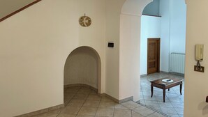 A spacious hallway with a tiled floor, a wooden staircase, and a wooden door at the end. - Stunning views, Space, Charm, Great Pool, Ideal Amalfi Coast location! (Furore)