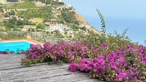A wooden deck with a pool and vibrant pink bougainvillea flowers. - Stunning views, Space, Charm, Great Pool, Ideal Amalfi Coast location! (Furore)