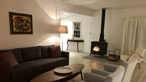 Ein Wohnzimmer mit Sofa, Sesseln, einem Couchtisch, einem Kamin und einem Bild an der Wand.