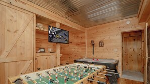 Ett rum med trägolv, ett fotbollsspel och en tv som är monterad på väggen.
