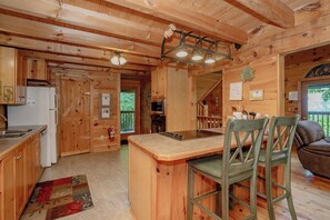 A wooden cabin interior with a kitchen, dining area, and a bar.