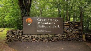 Señal para el Parque Nacional de las Montañas Humeantes, con un logotipo y texto.