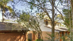 A residential property with a brick house, a garage, and a garden with various plants. - Barefoot Beach House Shoal Bay Retreat (Shoal Bay)