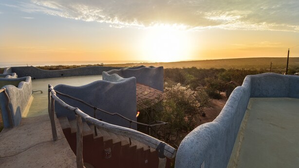 Eine Terrasse mit Blick auf einen Sonnenuntergang über einer Landschaft.
