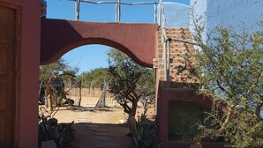 Ein Innenhof mit einem Steinweg, einer Holztür und einem Metallgitter.
