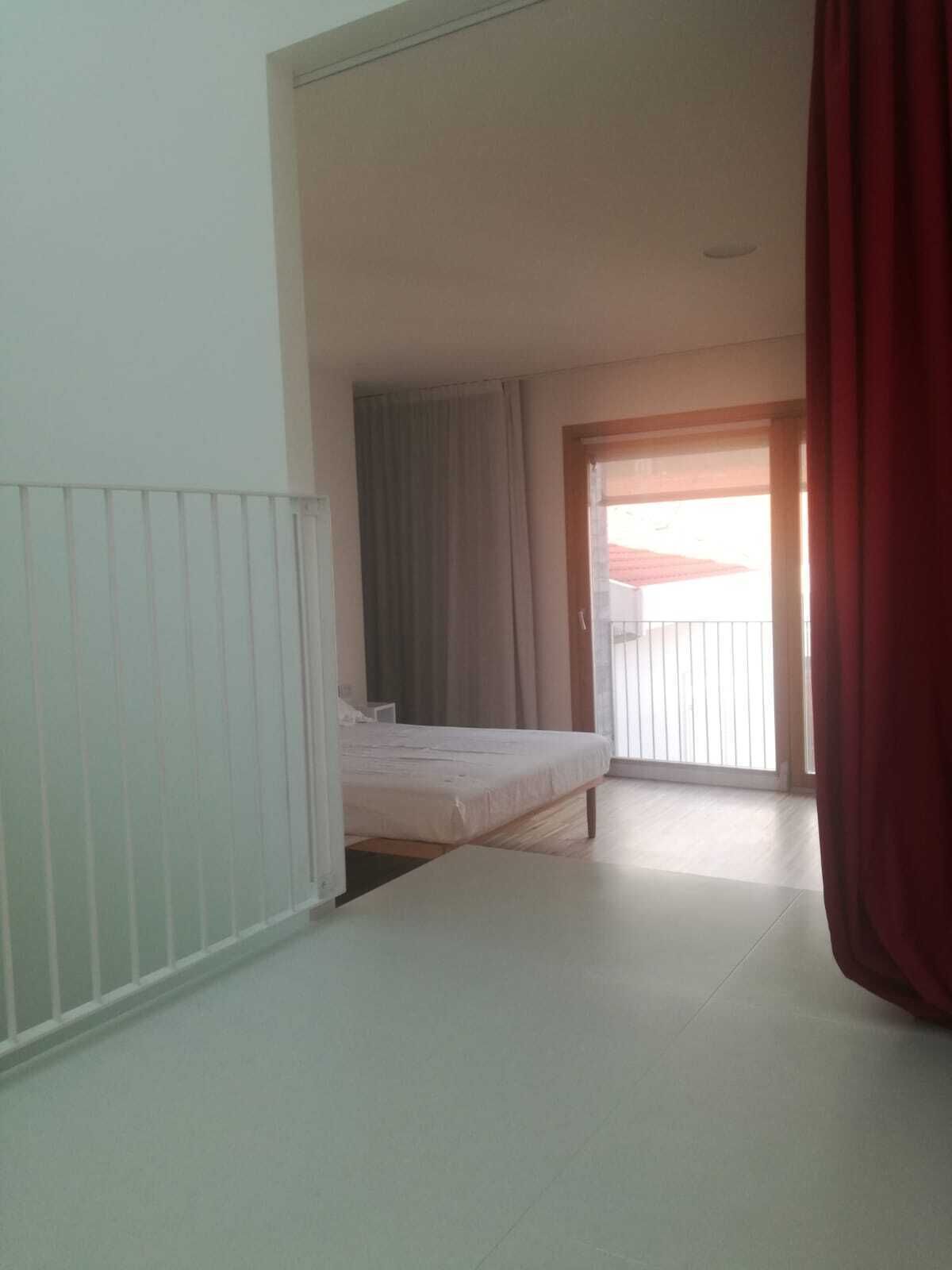 Een hotelkamer met een bed, een raam met gordijnen en uitzicht op buiten.