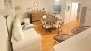 A spacious living area with a white sofa, a dining table with chairs, and a ceiling fan. - Charming Beach Cottage Duplex-Huge Upper Level  (Newport Beach)