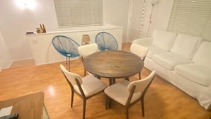 A modern living room with a round wooden table, white sofa, and blue chairs. - Charming Beach Cottage Duplex-Huge Upper Level  (Newport Beach)