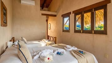 Une chambre d’hôtel avec deux lits, un plafond en bois, une fenêtre donnant sur un beau paysage et un climatiseur fixé au mur.