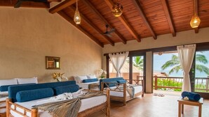 A room with wooden beds, a balcony with a view of palm trees, and a ceiling fan. - Luxury Eco Retreat in Troncones City (Troncones)
