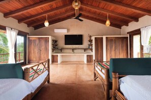 A room with two wooden beds, a television, and a ceiling fan. - Luxury Eco Retreat in Troncones City (Troncones)
