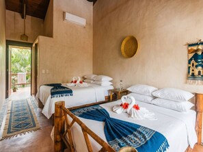 A hotel room with two beds, a wooden chair, a blue and white patterned rug, and a wall-mounted decorative plate.