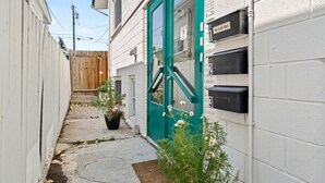 A narrow alleyway with a green door, numbered mailboxes, and a wooden fence. - Ramsay Manor | Spacious 1BR Queen Bed Inner City (Calgary)
