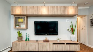 A modern living room with a flat-screen TV mounted on a wooden wall unit. - Ramsay Manor | Spacious 1BR Queen Bed Inner City (Calgary)