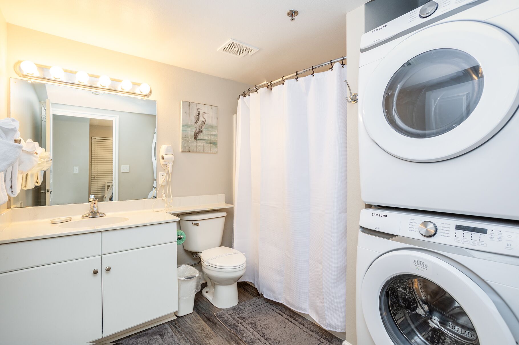 A compact bathroom with a sink, toilet, and stacked washer-dryer unit.