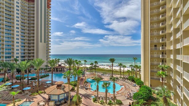 Ein Resort mit mehreren Schwimmbecken, Palmen und Meerblick.