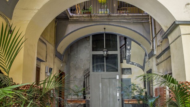 An arched entrance with potted plants, a wooden door, and a balcony with railings. - 26 Urban Guest House (Naples)