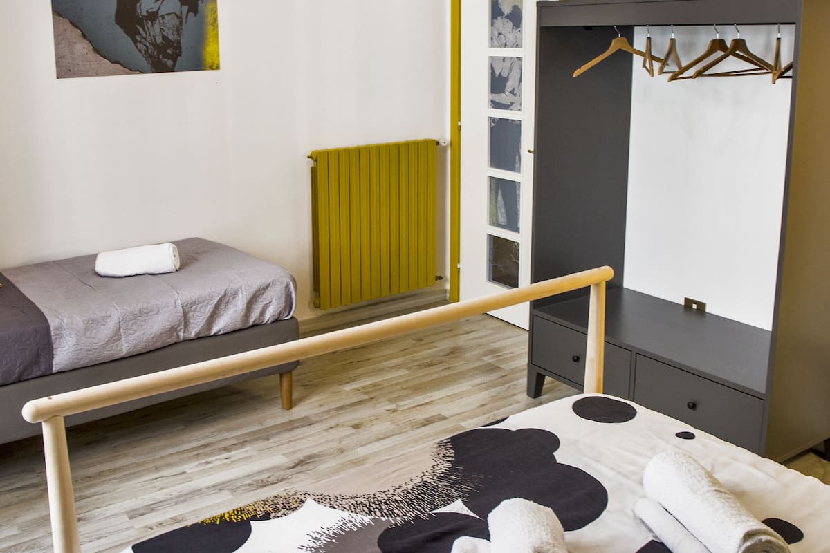 Un dormitorio con cama, un banco, un armario y un radiador.