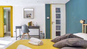 A modern hotel room with a yellow bed, a desk with a chair, and a door with a teal accent. - 26 Urban Guest House (Naples)