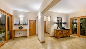 Un pasillo espacioso con una consola de madera, un jarrón decorativo y un espejo encima.