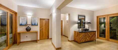 A spacious hallway with a wooden console table, a decorative vase, and a mirror above it.