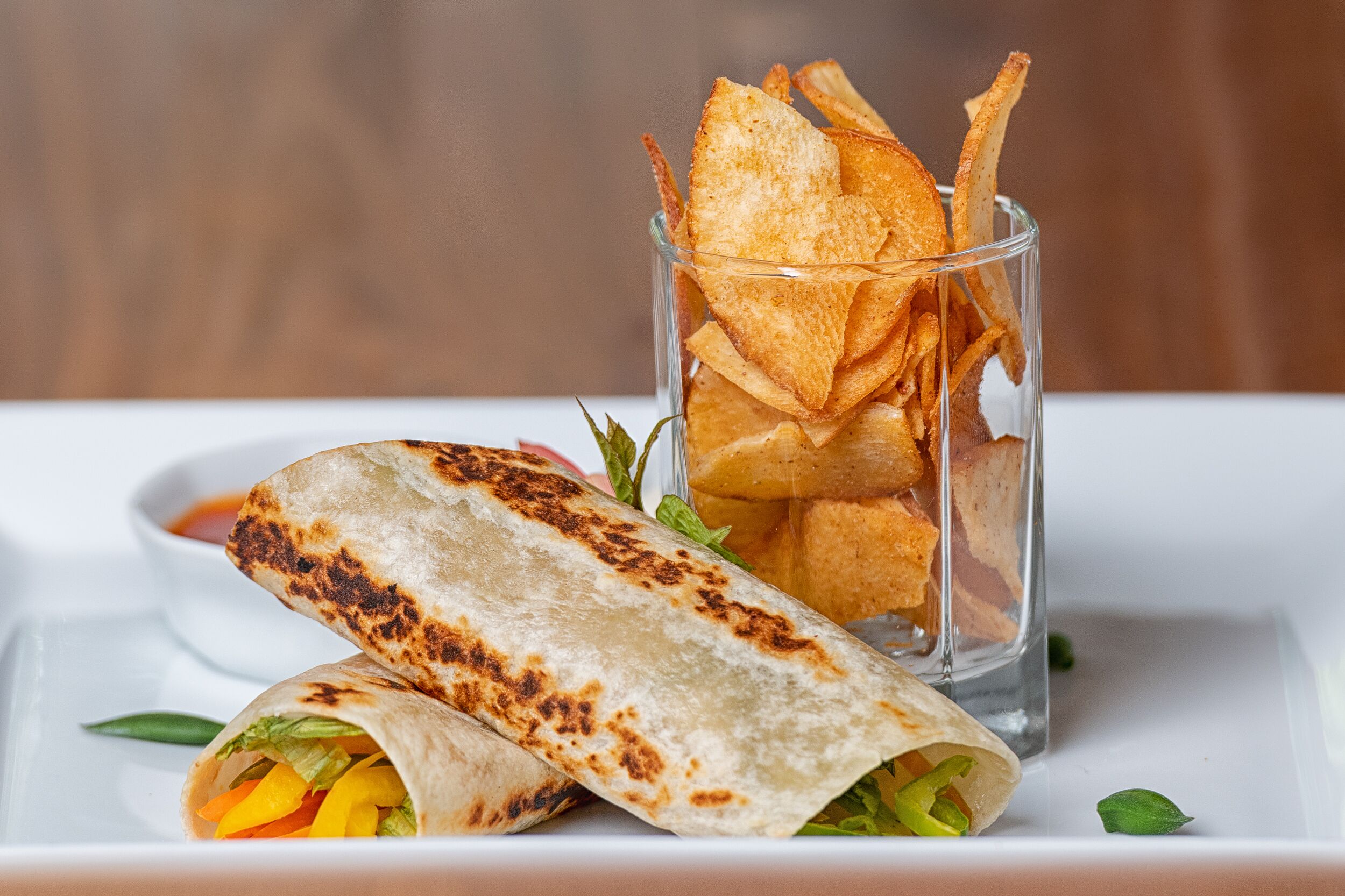 Une assiette avec une tortilla pliée et un verre de chips de tortilla.