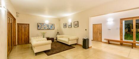 A spacious living room with two white sofas, a coffee table, and a wooden bench.