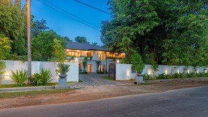 Una casa moderna con camino de entrada pavimentado, acceso mediante portón y jardines bien cuidados.