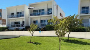 A modern building with a flat roof, large windows, and a balcony with a metal railing. - Beautiful new apartment with swimming pool on the Portuguese Silver Coast (Salir do Porto)