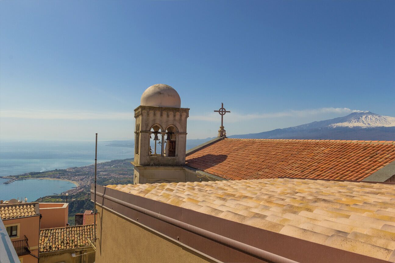 Ein Gebäude mit einem Ziegeldach, einem Glockenturm und einem Kreuz auf der Spitze.