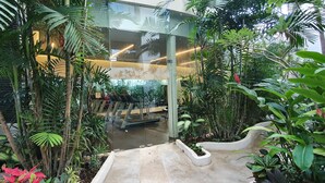 A modern indoor space with glass walls, surrounded by lush greenery and plants. - New condo in best building Playa, 1 block from beach, amazing rooftop pool (Zazil-ha)