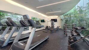 A modern gym with treadmills, weight machines, and a TV screen. - New condo in best building Playa, 1 block from beach, amazing rooftop pool (Zazil-ha)