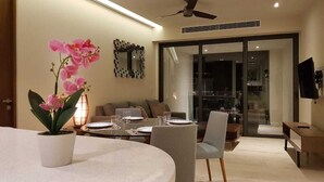 A modern dining area with a round table, chairs, and a potted orchid. - New condo in best building Playa, 1 block from beach, amazing rooftop pool (Zazil-ha)