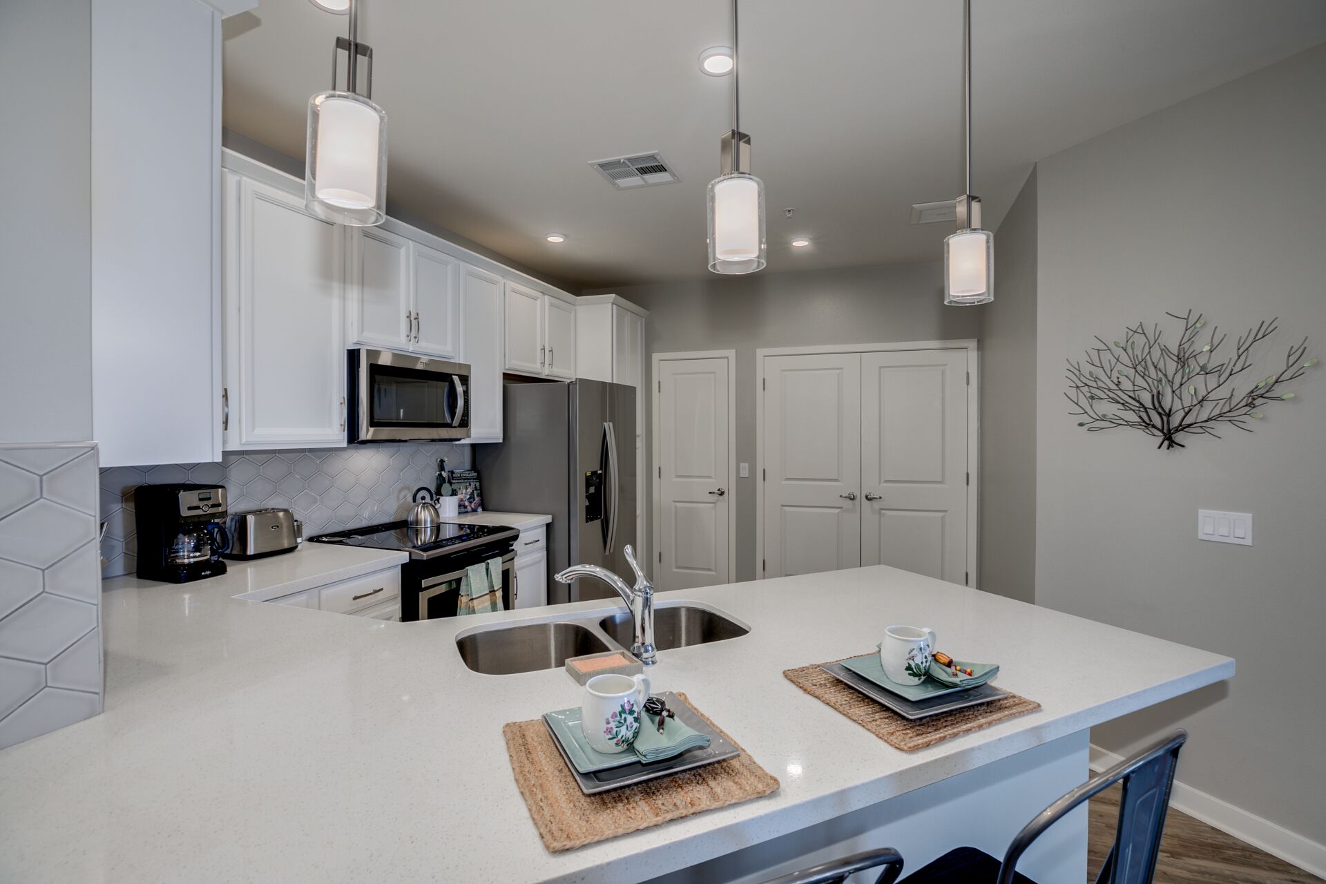A modern kitchen with white cabinets, stainless steel appliances, and pendant lighting.