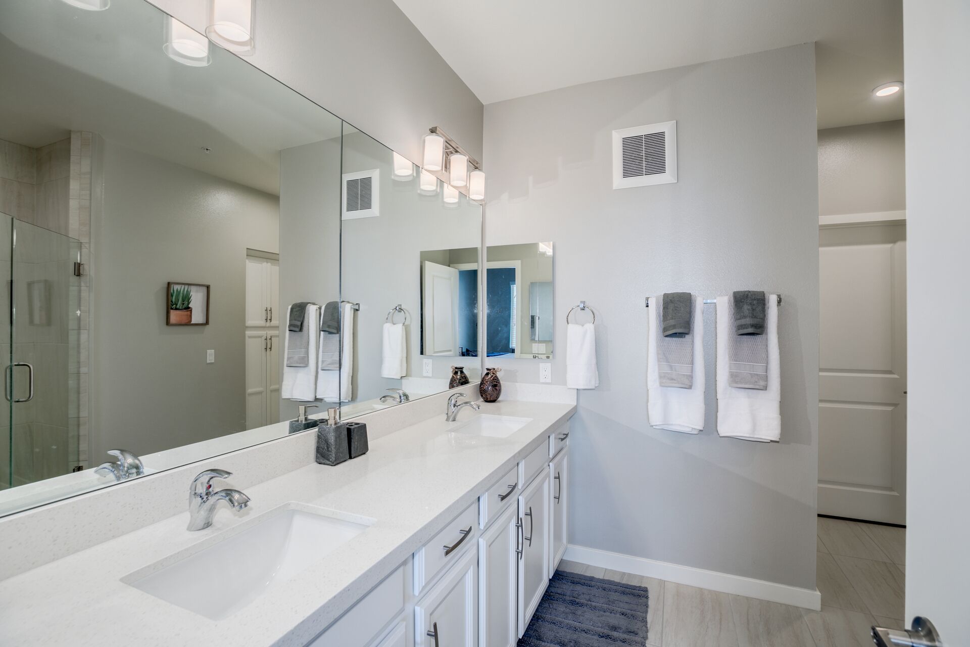 Une salle de bain moderne dotée d’un grand miroir, de deux vasques et d’une douche à parois de verre.