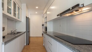 Una cocina moderna con muebles blancos, un refrigerador de acero inoxidable y un microondas integrado.
