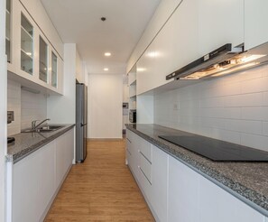 Une cuisine moderne avec des meubles blancs, un réfrigérateur en acier inoxydable et un four à micro-ondes encastré.