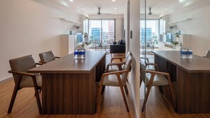 Una sala de conferencias moderna con una larga mesa, sillas y vistas a la ciudad a través de amplios ventanales.
