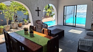Un patio amplio con piscina, mobiliario exterior y plantas en macetas.