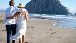 A couple walking on a beach with a large rock formation in the background. - AMAZING, OCEAN VIEWS,
MORRO 🪨, JACUZZI, WIFI, PARKING (Morro Bay)
