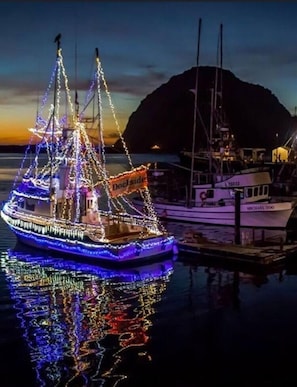 A boat adorned with colorful lights docked at a marina with a mountainous backdrop. - AMAZING LOCATION,LOCATION OCEAN VIEWS,
MORRO 🪨, JACUZZI, PARKING (Morro Bay)
