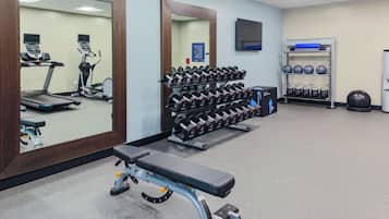 A gym with treadmills, dumbbells, kettlebells, and a bench.