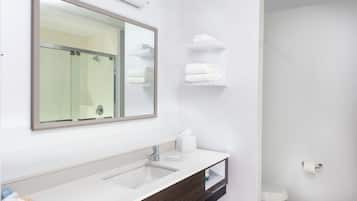 Une salle de bain moderne avec un grand miroir, un lavabo et des toilettes.