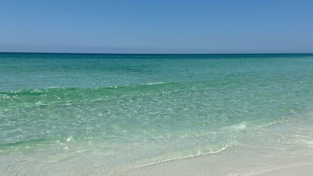 Une plage à l’eau turquoise et au sable blanc.